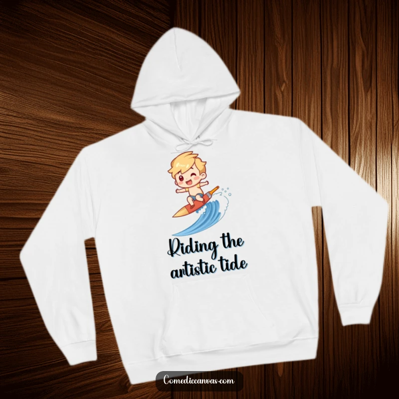 Funny hoodie featuring a character gleefully surfing a paintbrush down a canvas wave, offering cozy comfort for creatives.