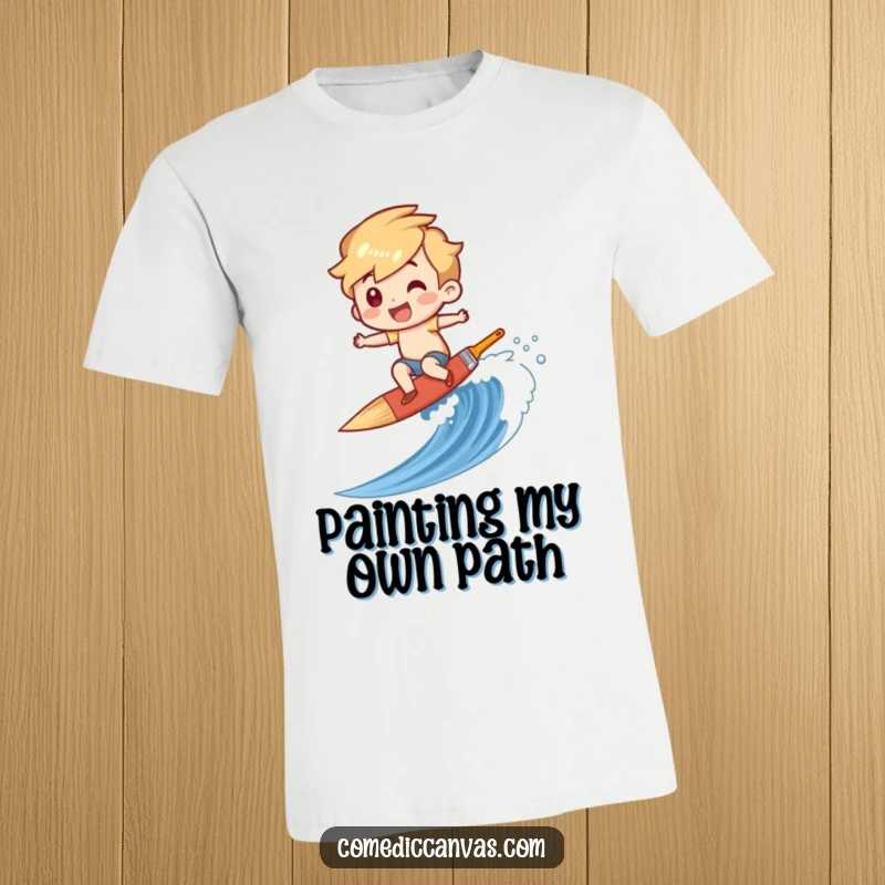 Funny t-shirt showing a character giggling while surfing a paintbrush down a canvas wave, embodying artistic freedom and fun.